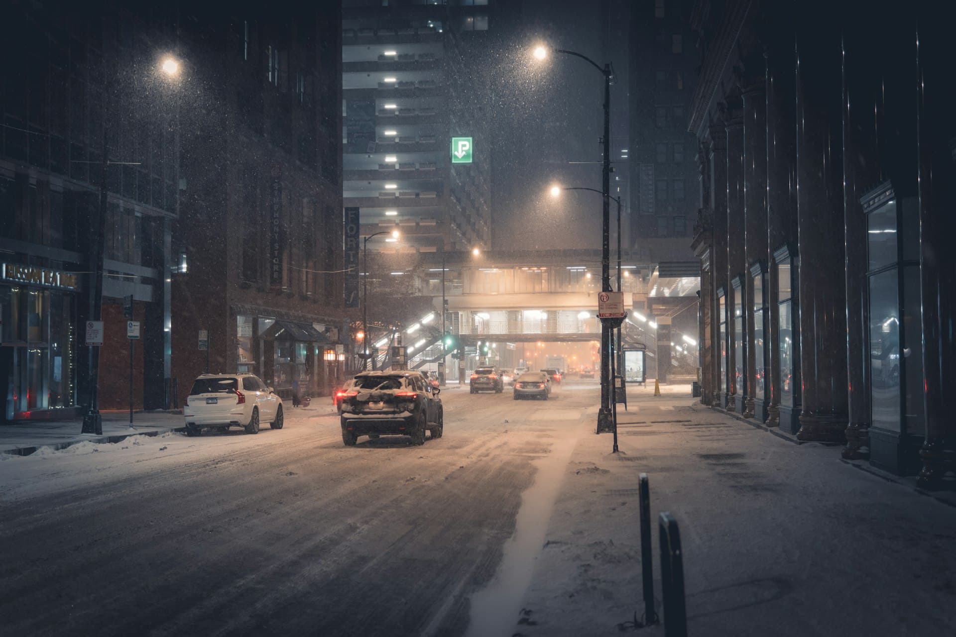 Chicago street during winter snowstorm with L train tracks and snowy conditions
