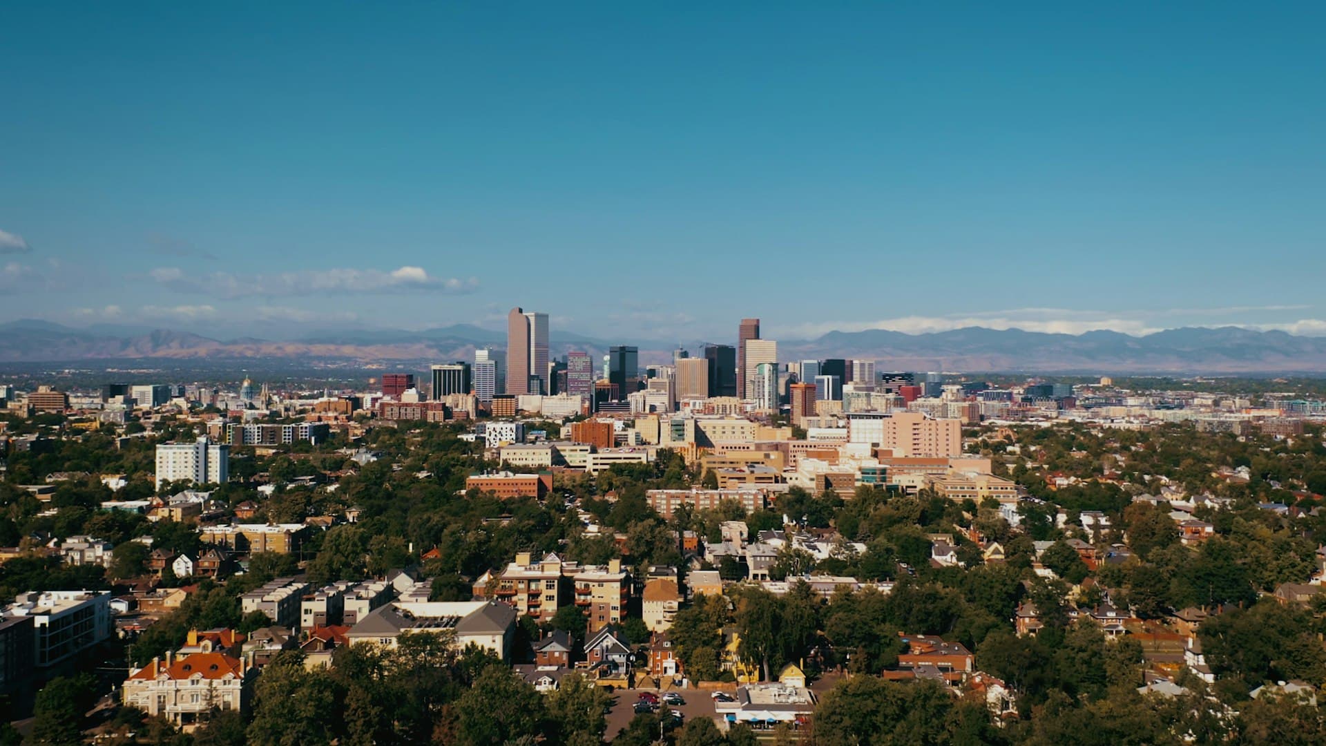 Downtown Denver skyline with Rocky Mountains in the background on a clear summer day