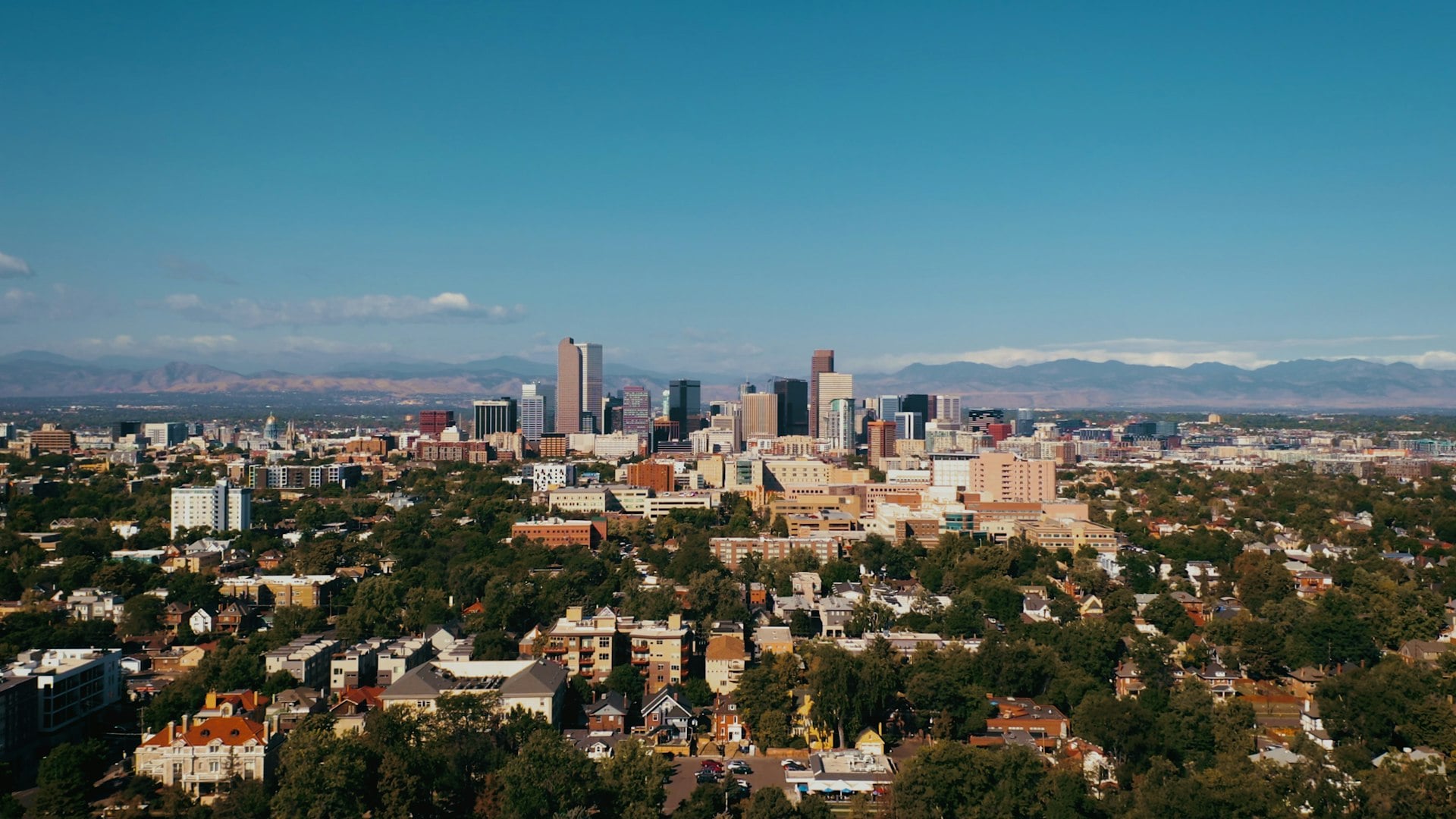 Downtown Denver skyline with Rocky Mountains in the background on a clear summer day