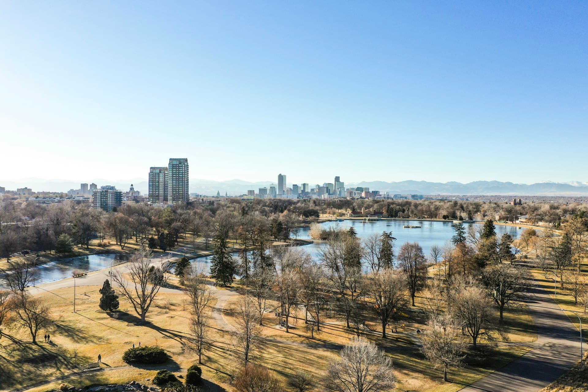 Aerial view of Denver City Park with downtown skyline and Rocky Mountains