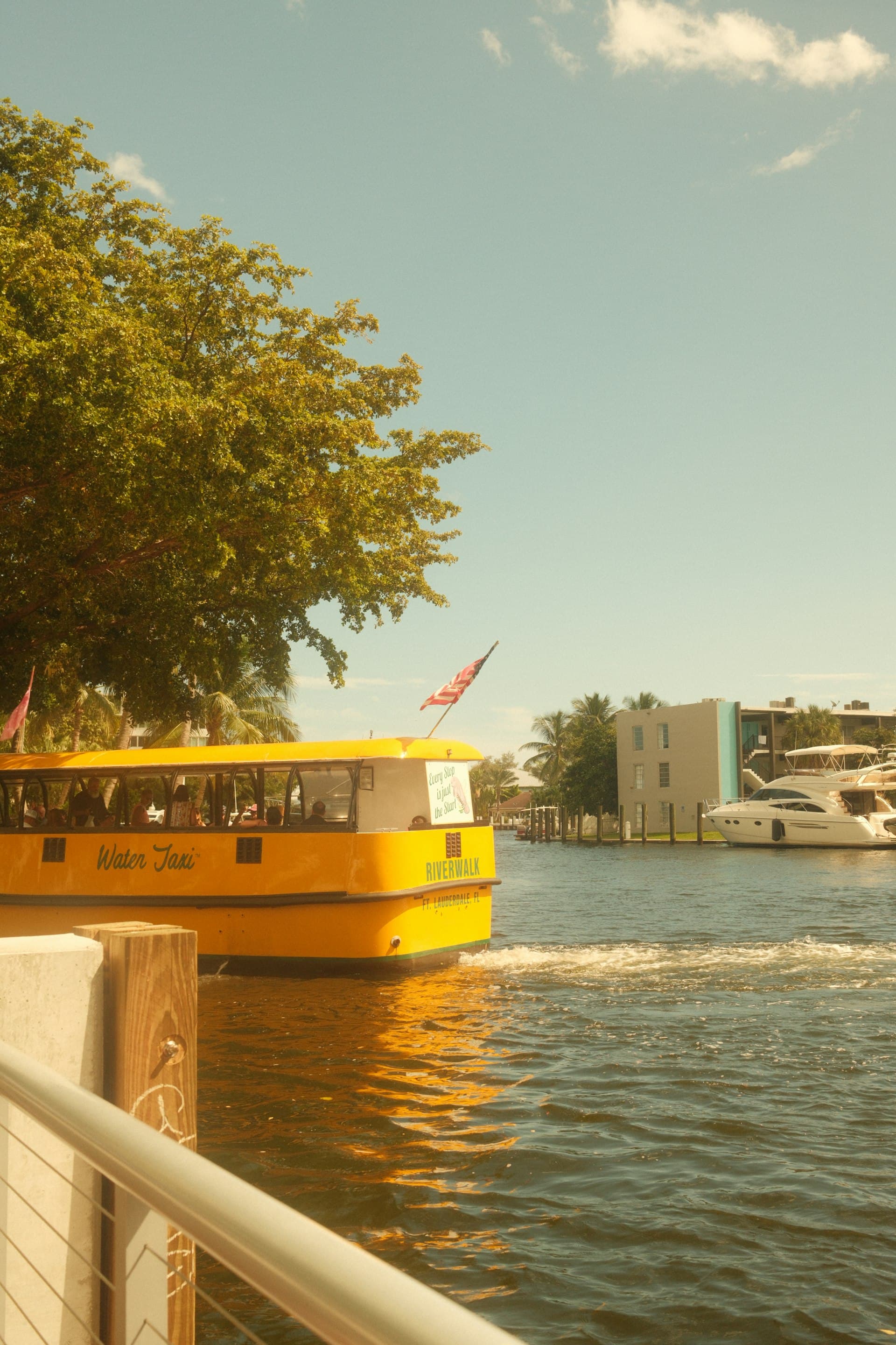 Fort Lauderdale Water Taxi yellow boat on the Riverwalk with waterfront buildings