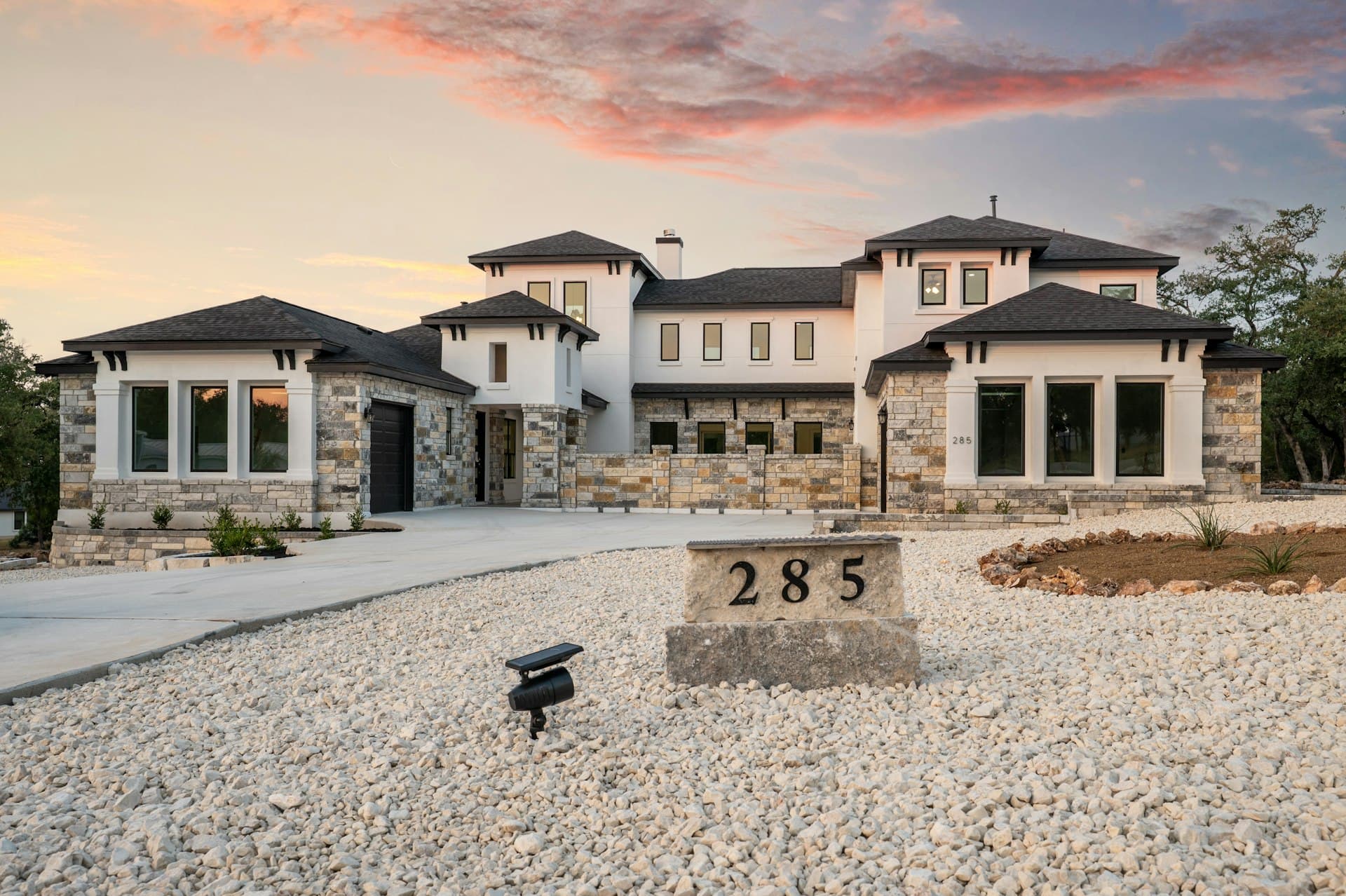 Luxury Texas home with stone accents and modern roofing at sunset