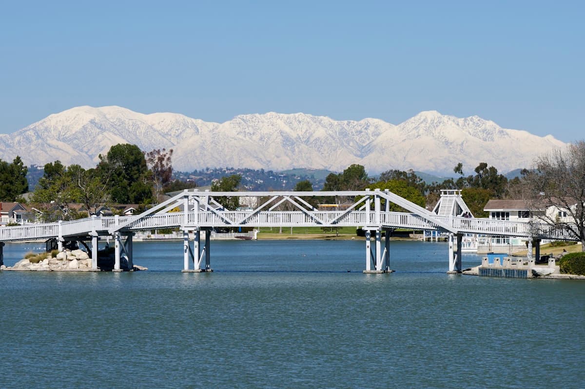 Bridge over lake in Woodbridge Irvine with snow-capped mountains in background