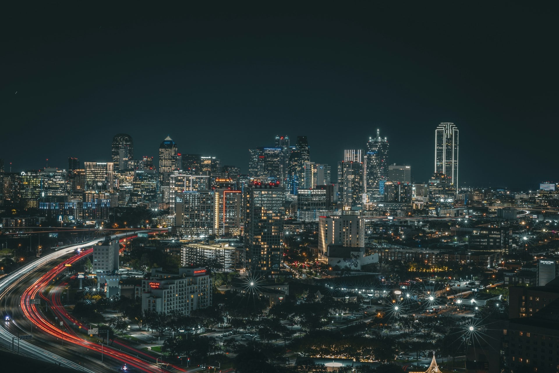 Dallas Fort Worth skyline at night with highway light trails and illuminated skyscrapers