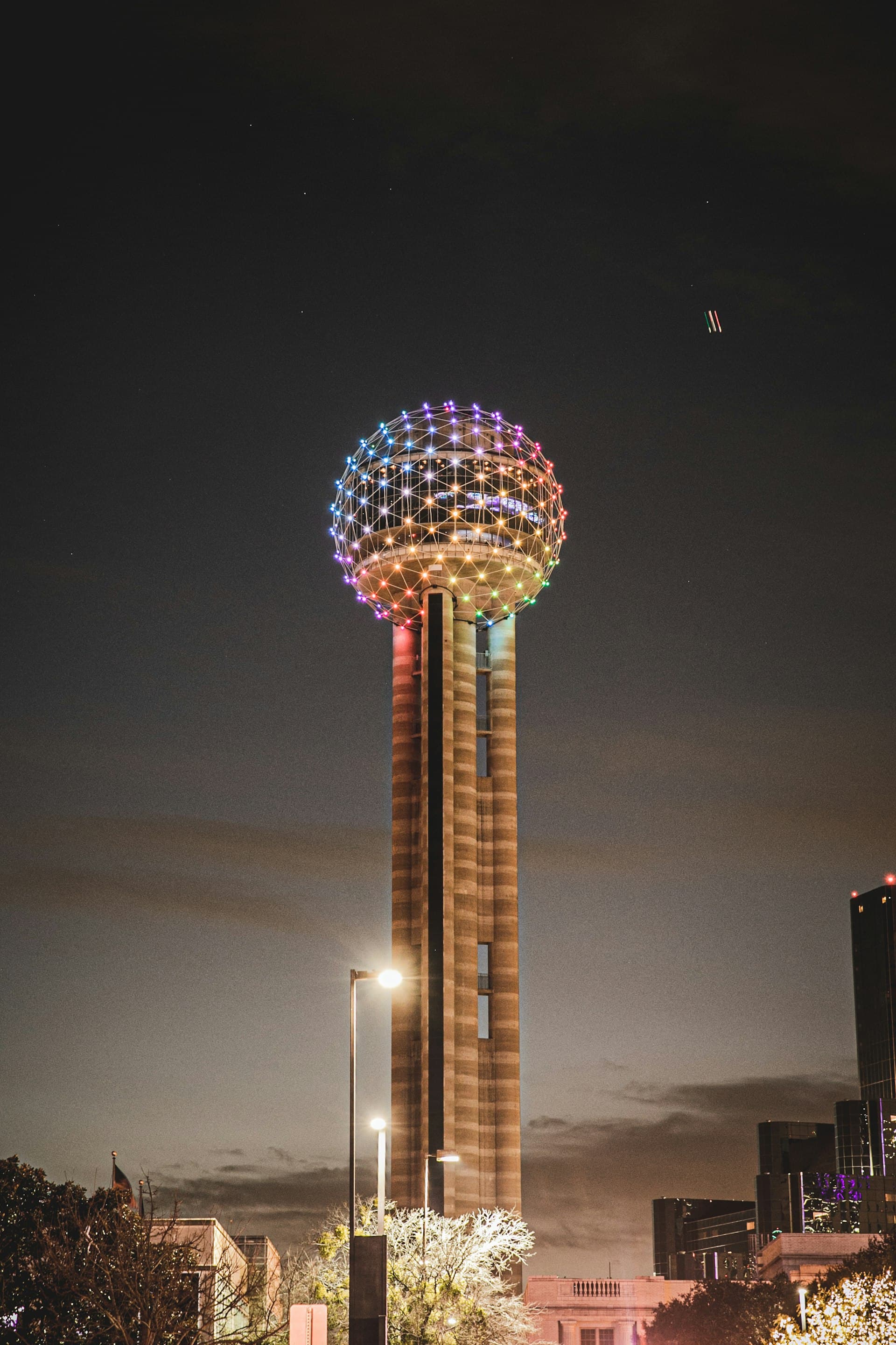 Reunion Tower in downtown Dallas lit up with colorful lights at night