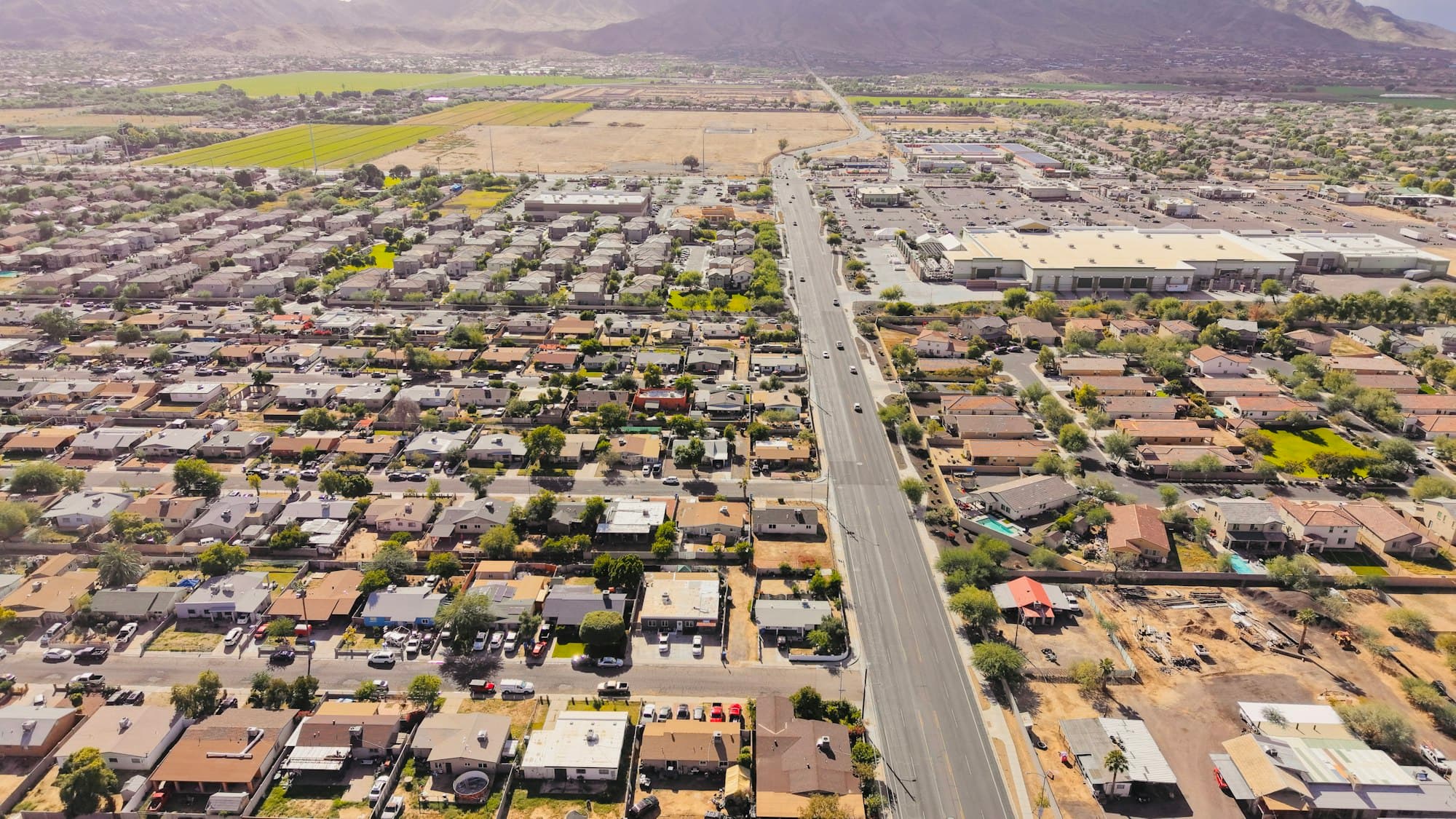 Aerial view of suburban neighborhood with tile roofs and desert mountains