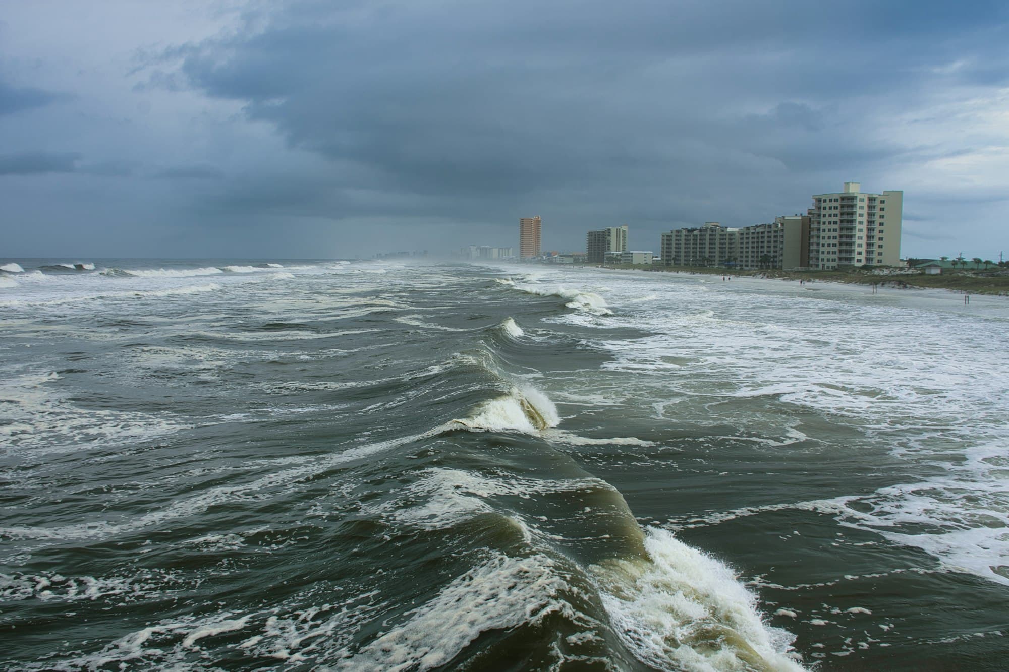 Florida hurricane storm waves with dark clouds over coastal buildings