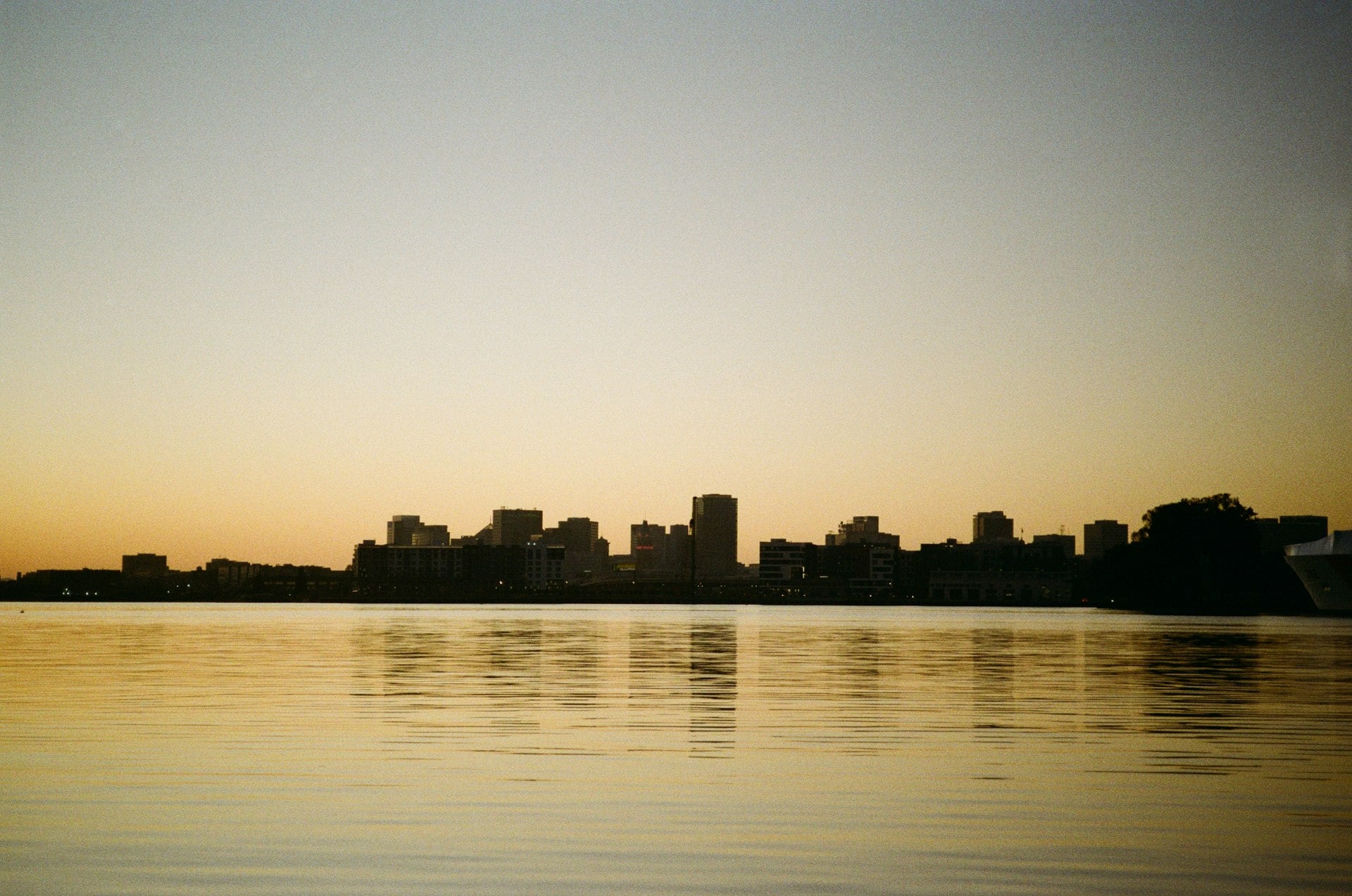 Oakland California skyline reflected in calm water at sunset