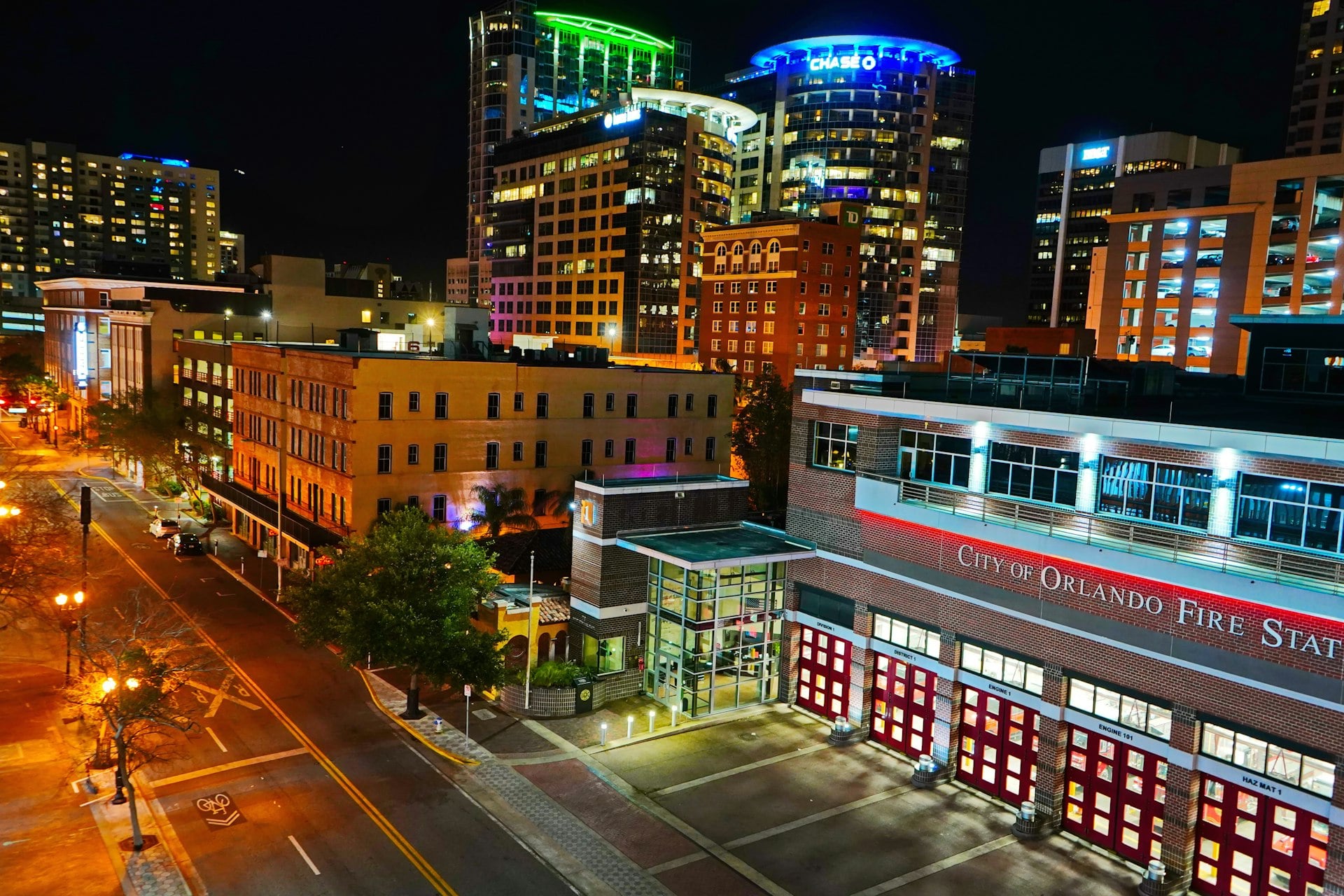 Downtown Orlando Florida cityscape at night with illuminated buildings and City of Orlando Fire Station