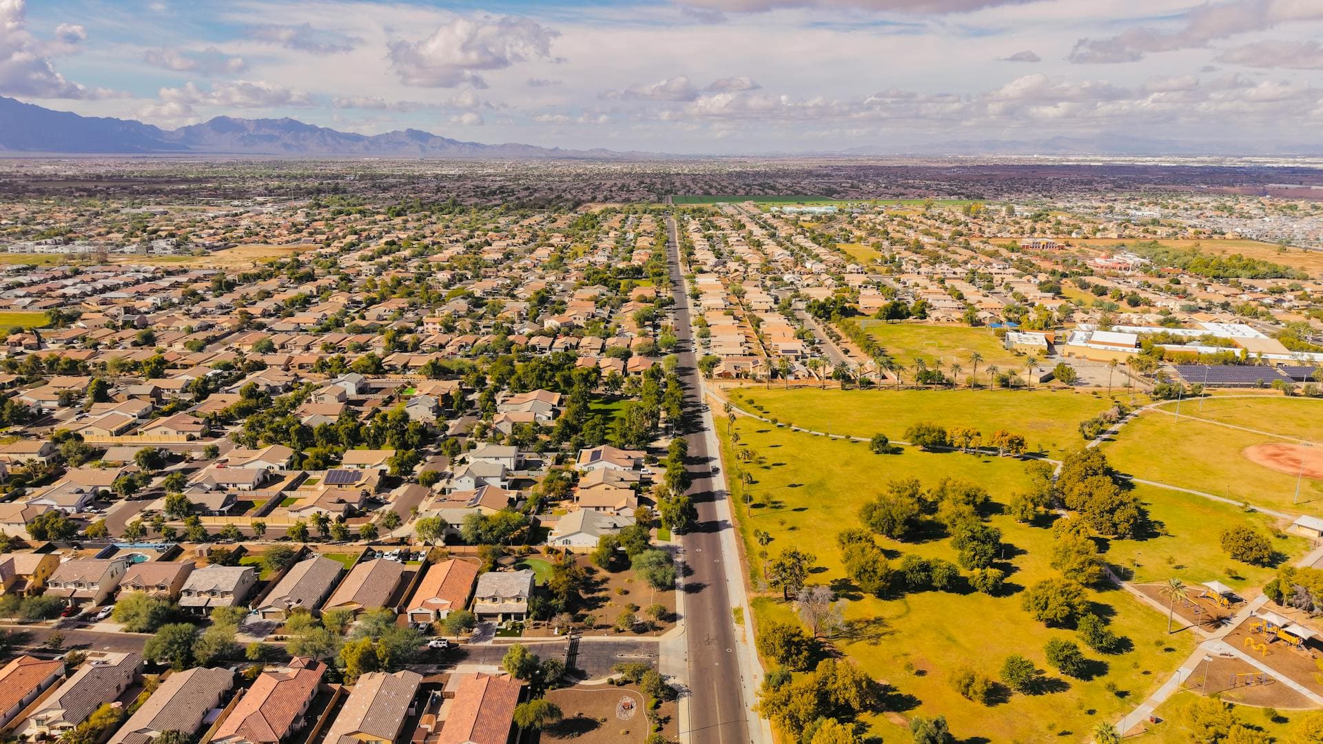 Aerial view of suburban Arizona landscape showing residential homes with tile roofs and community parks