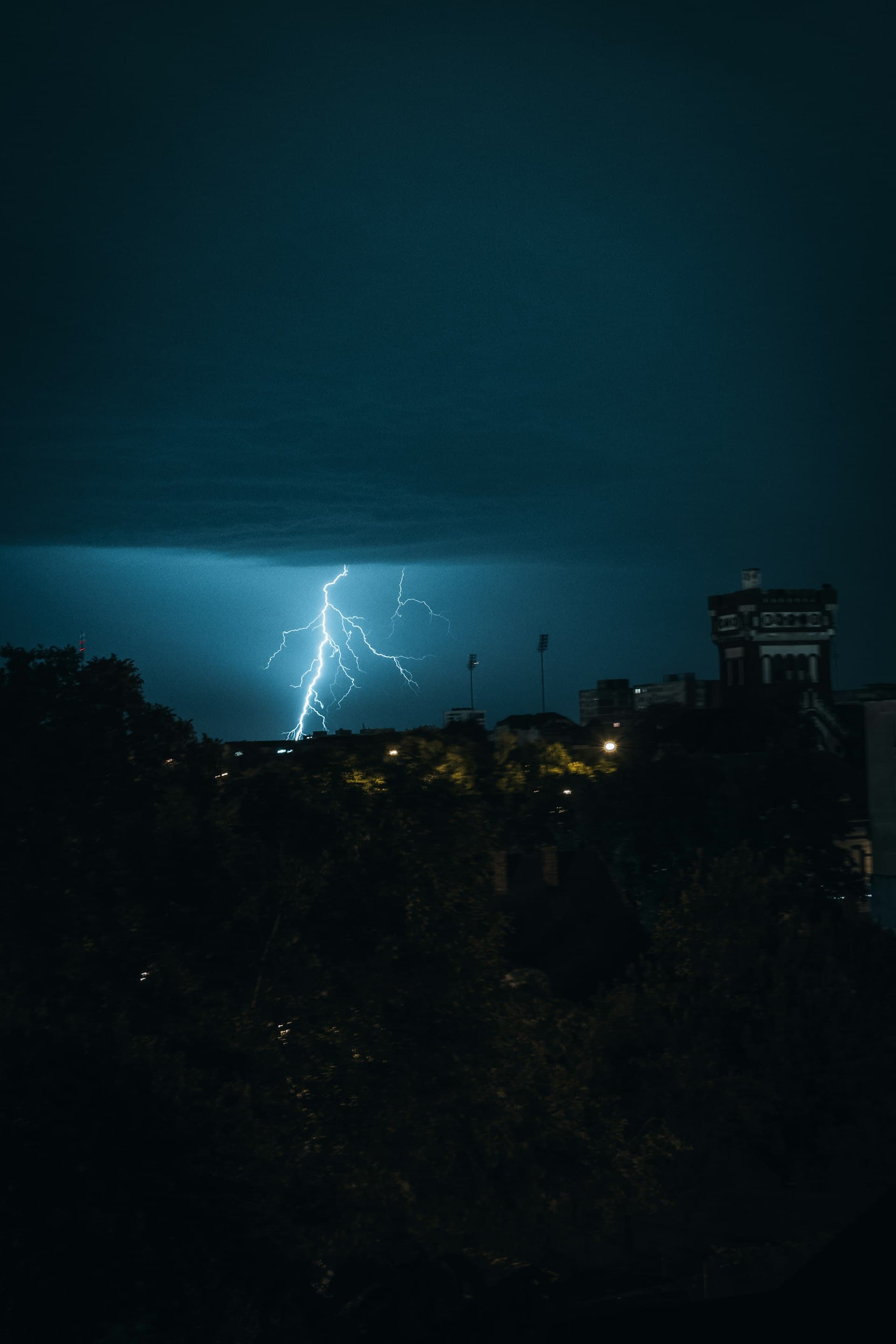 Dramatic lightning strike over city at night during thunderstorm showing monsoon weather conditions