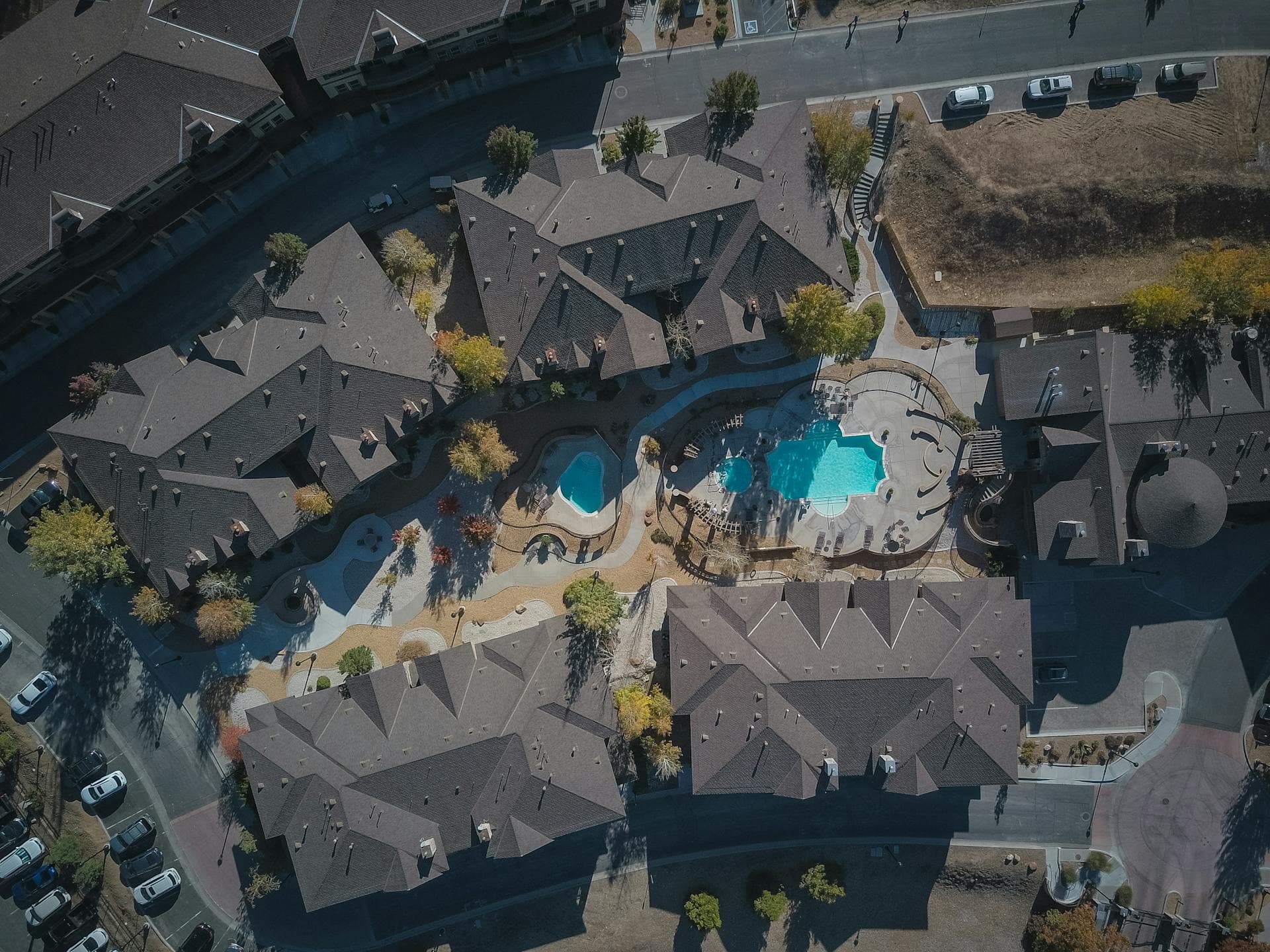 Aerial view of suburban residential community with gray rooftops and swimming pools