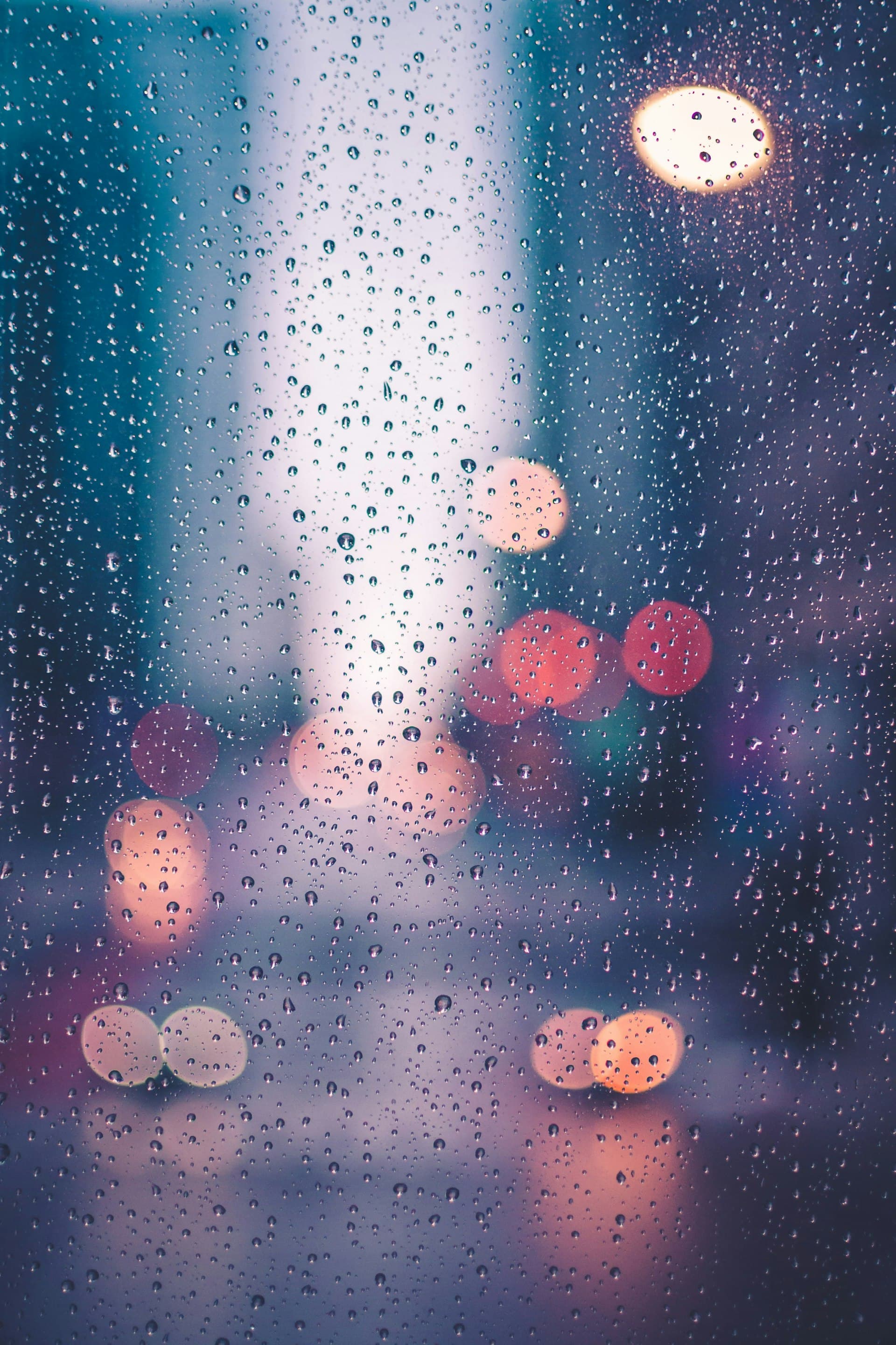 Raindrops on window with city lights representing Portland rainy climate