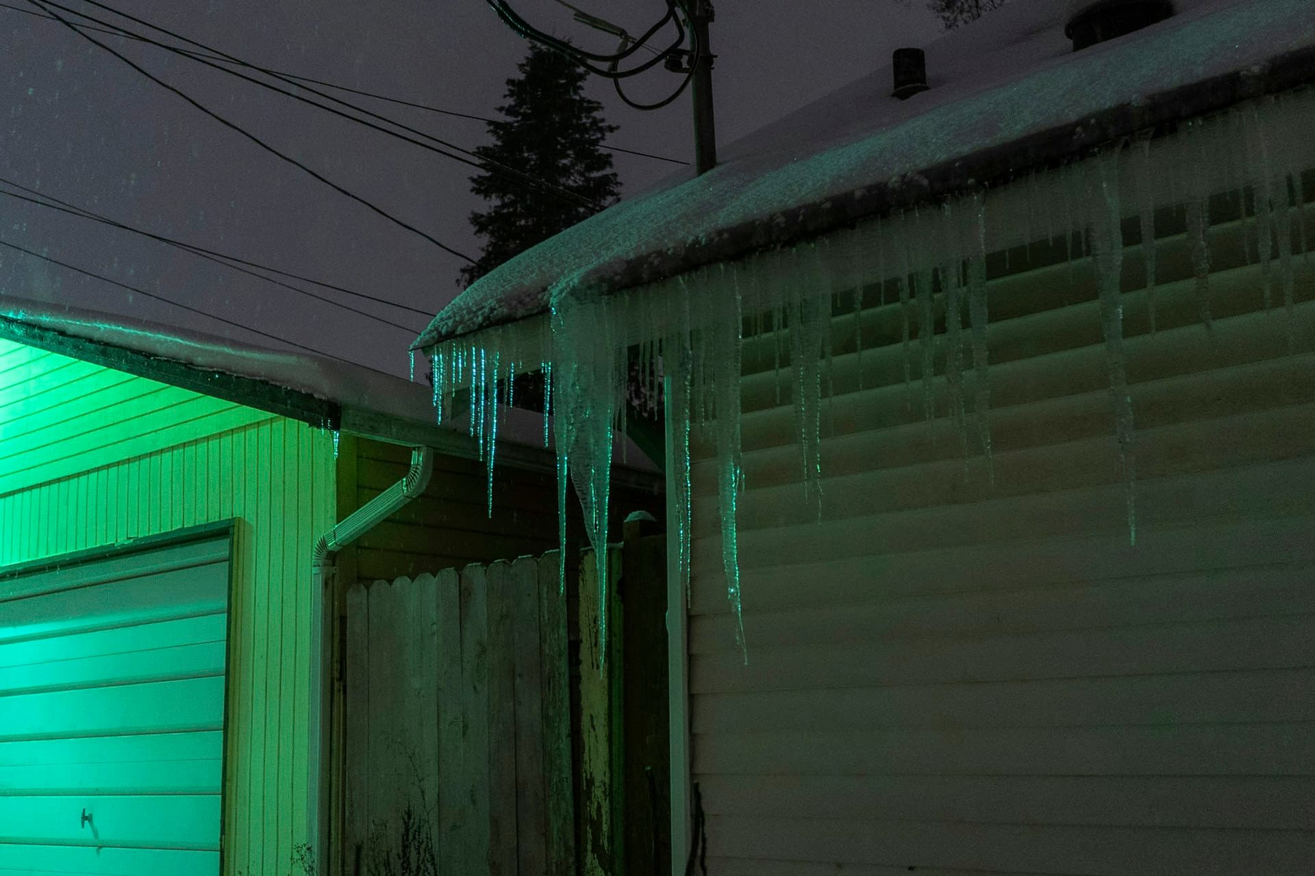 House with icicles forming on roof eaves demonstrating ice dam conditions