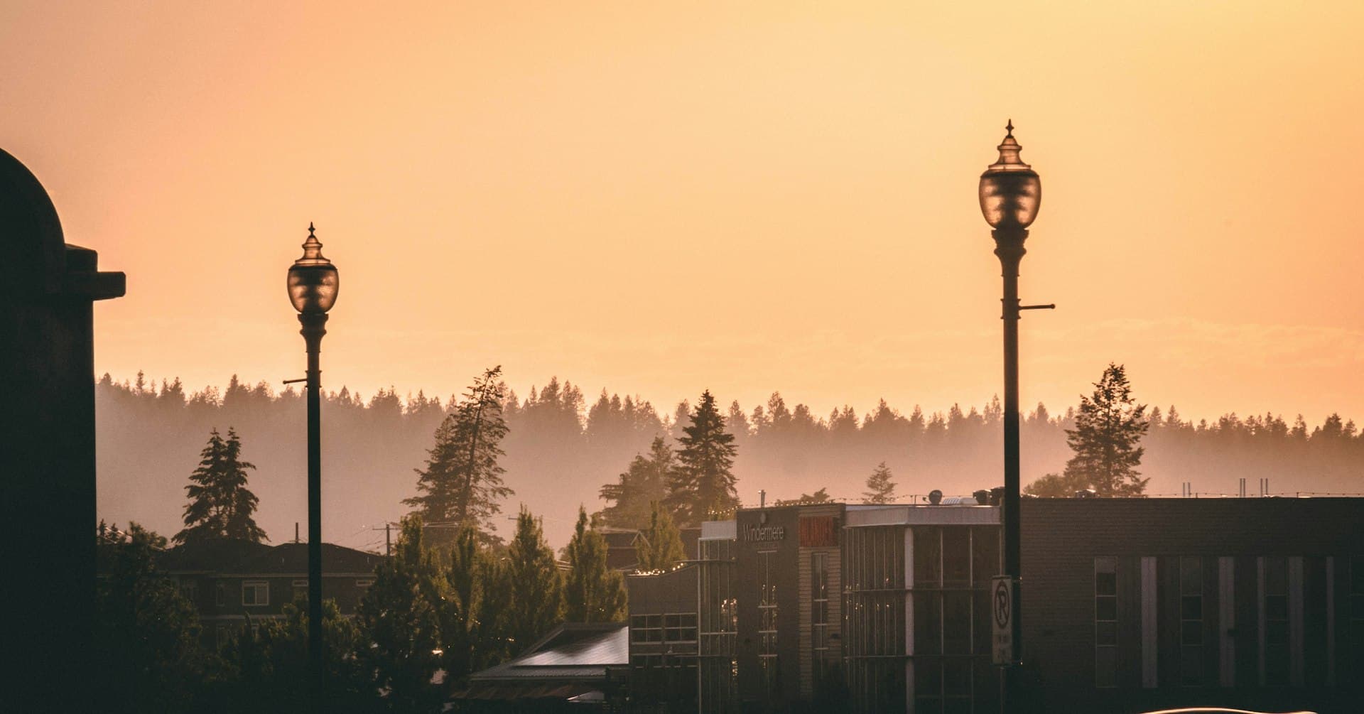Spokane cityscape at sunset with pine tree-lined hills and street lamps