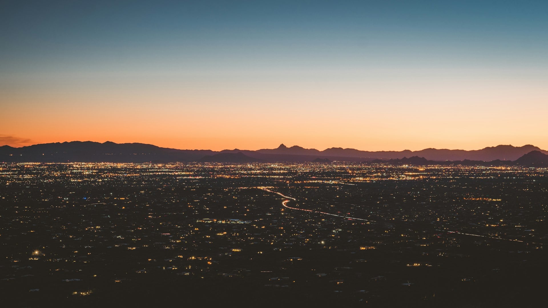 Tucson Arizona skyline at sunset with mountain silhouettes and city lights